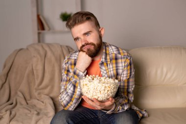 Kanepede televizyon izleyen bekar bir adam.