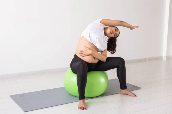 Joven mujer embarazada flexible haciendo gimnasia con pelota de fitness. El concepto de preparar el cuerpo para el parto fácil —  Fotos de Stock