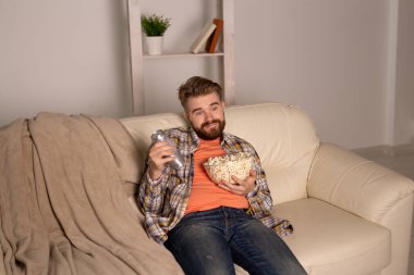 Kanepede televizyon izleyen bekar bir adam.