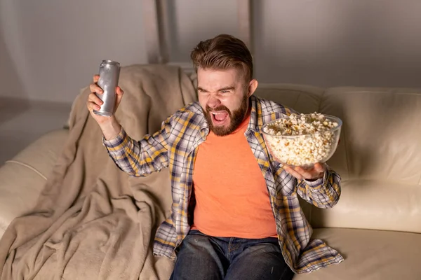 Pria berjenggot menonton film atau permainan olahraga TV makan popcorn di rumah di malam hari. Sinema, kejuaraan dan konsep waktu luang. — Stok Foto