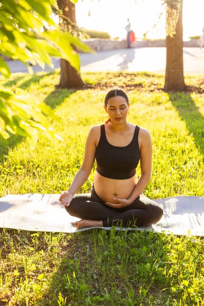 Ung gravid kvinna mediterar i naturen, utövar yoga. Vård av hälsa och graviditet — Stockfoto