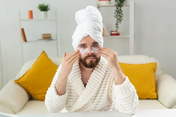 Hombre barbudo aplicándose parches en la cara. Arrugas y cuidado en el hogar de la cara para los hombres. —  Fotos de Stock