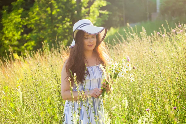 Giovane donna raccogliere fiori nel prato in estate sera — Foto Stock