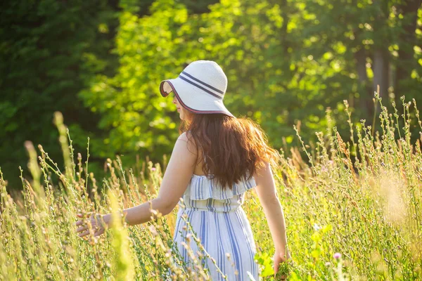 Giovane donna raccogliere fiori nel prato in estate sera — Foto Stock