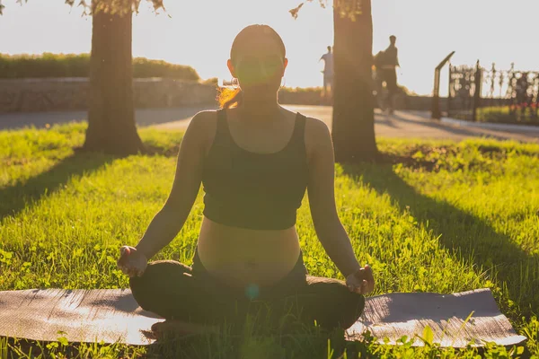 Ung gravid kvinna mediterar i naturen, utövar yoga. Vård av hälsa och graviditet — Stockfoto