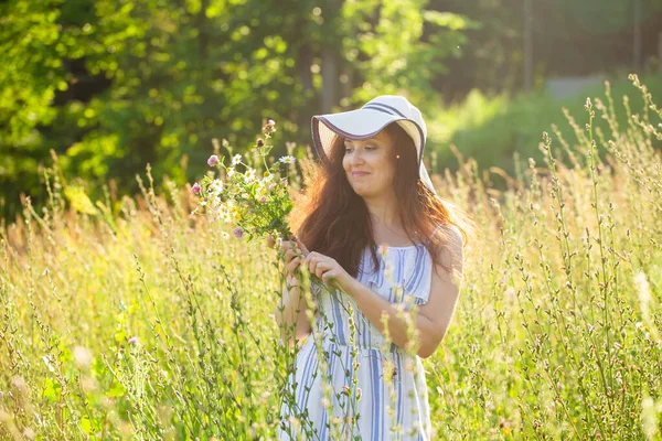 Giovane donna raccogliere fiori nel prato in estate sera — Foto Stock