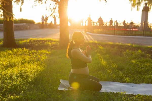 Ung gravid kvinna mediterar i naturen, utövar yoga. Vård av hälsa och graviditet — Stockfoto