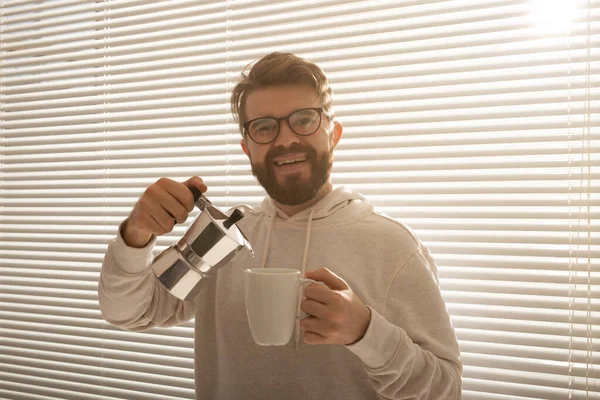 Młody człowiek nalewa rano kawę z moka pot. Śniadanie i przerwa koncepcja. — Zdjęcie stockowe