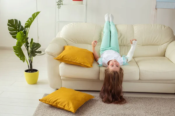 Kind met een gips om een gebroken pols of arm lachend en plezier hebbend op een bank. Positieve houding, herstel en kind concept. — Stockfoto