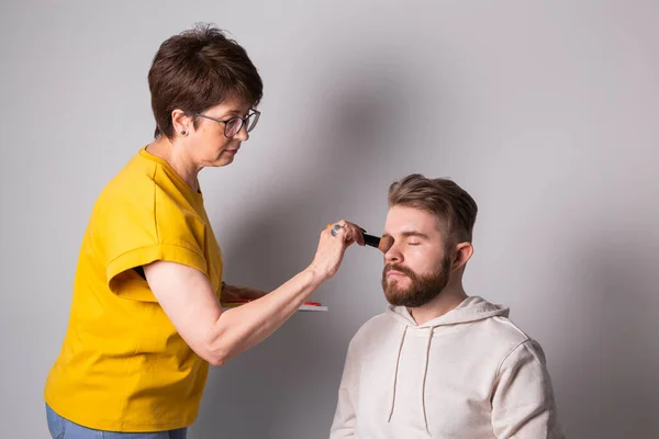 Profesyonel makyöz stüdyoda genç adam makyajı yapıyor. — Stok fotoğraf