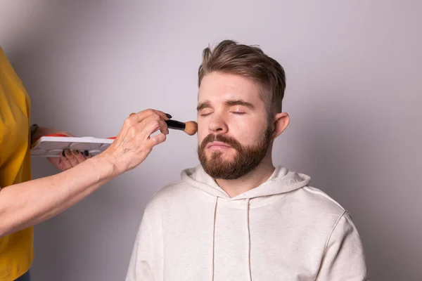 Професійний візажист робить макіяж молодого чоловіка в студії — стокове фото