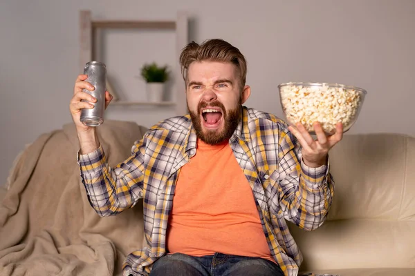 Pria berjenggot menonton film atau permainan olahraga TV makan popcorn di rumah di malam hari. Sinema, kejuaraan dan konsep penggemar. — Stok Foto