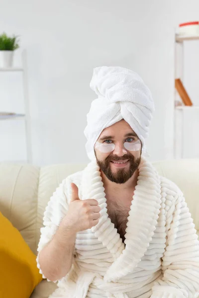 Bearded man sitting with eye patches on his face. Wrinkles and face home care for men. — Stock Photo, Image