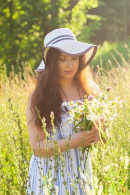 Yaz akşamları çayırda çiçek toplayan genç bir kadın.