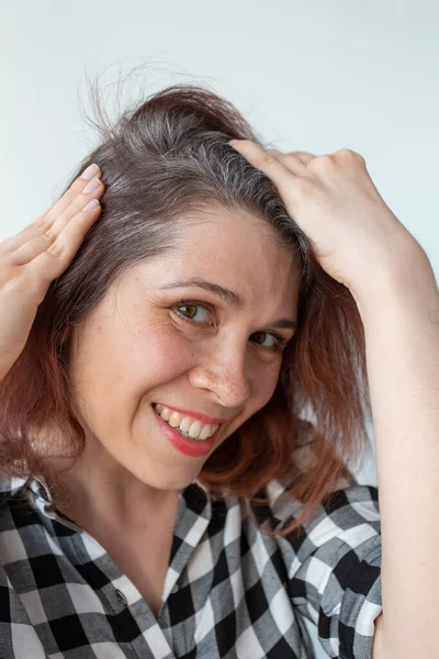 Молода жінка показує своє сіре коріння волосся. Концепція раннього старіння . — стокове фото