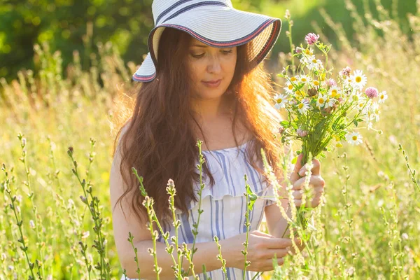 Jeune femme cueillant des fleurs dans la prairie en soirée d'été — Photo