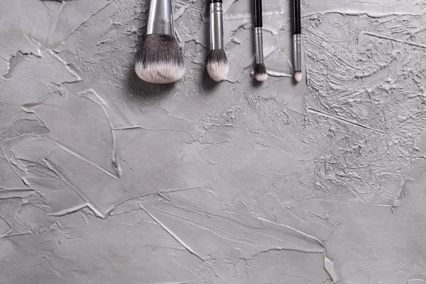 Top view of make-up brushes on grey background with copyspace