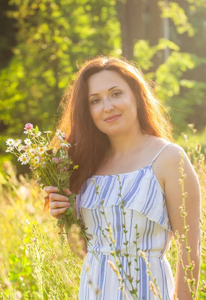 Молода жінка збирає квіти на лузі в літній вечір — стокове фото