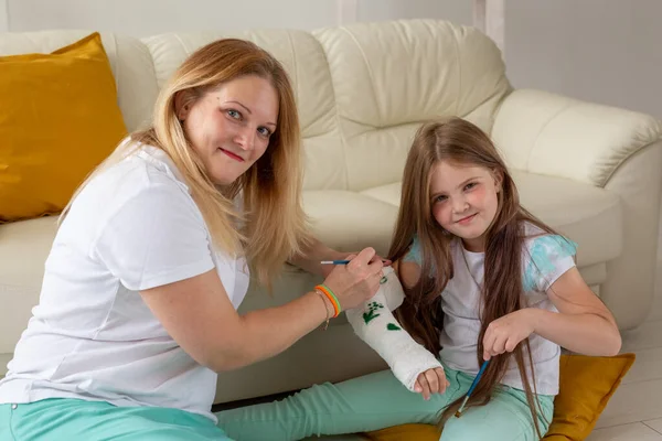 Madre e hija dibujando el cuadro en el vendaje usando pinturas. concepto de terapia de juego. —  Fotos de Stock