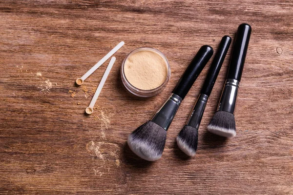 Mineral powder of nude colors with a spoon dispenser for make-up on wooden background