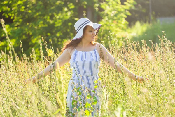 Vrouw wandelen in een veld in de zomer zonnige dag. — Stockfoto