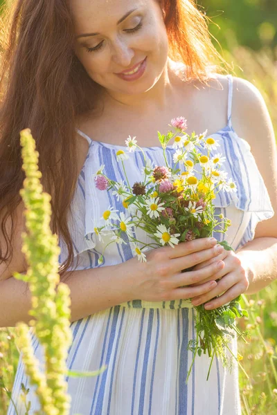 Giovane donna raccogliere fiori nel prato in estate sera primo piano. — Foto Stock