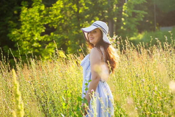 Jeune femme cueillant des fleurs dans la prairie en soirée d'été — Photo