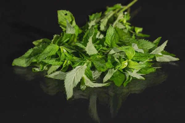 Mint leaves on black background. Peppermint lying on table — Stock Photo, Image