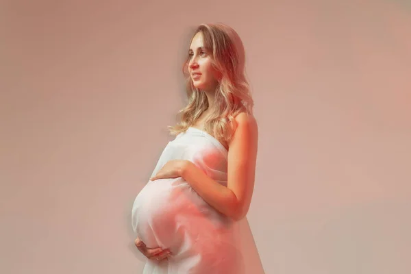 Элегантная беременная женщина, стоящая в светлой ткани. Беременность, фантазия и концепция сказки. — стоковое фото