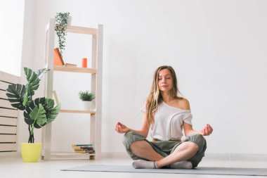 Nilüfer pozisyonunda meditasyon yapan genç bir kadın. Farkındalık pratiği, refah ve öz kavram.