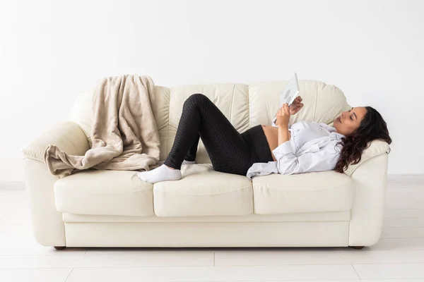 Femme enceinte latine utilisant un ordinateur tablette alors qu'elle était allongée sur le canapé à la maison. Grossesse et information pour le concept de parentalité. — Photo