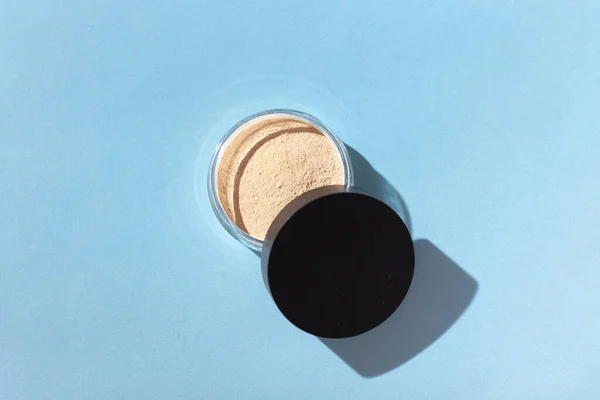 Mineral powder foundation isolated on blue background. Eco-friendly and organic beauty products