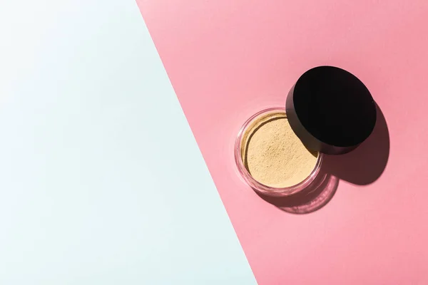 Mineral powder foundation isolated on pink and mint background with copy space. Eco-friendly and organic beauty products