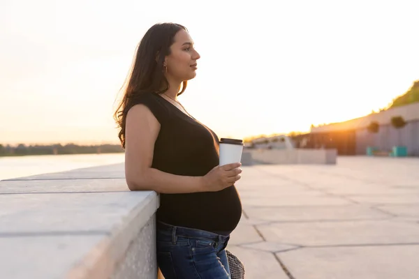 Hispanic pregnant woman drinking take away coffee outdoors. Copyspace. — Stockfoto