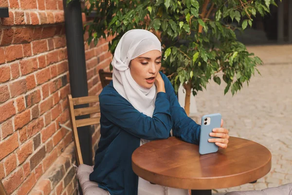 Happy muslim woman having video call on smartphone in outdoor cafe. — Φωτογραφία Αρχείου