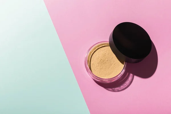 Mineral powder foundation isolated on pink and mint background with copy space. Eco-friendly and organic beauty products