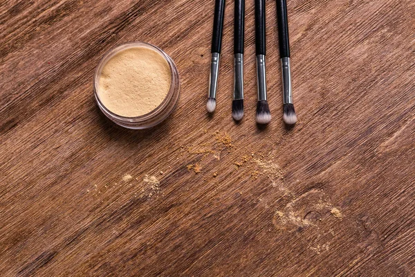 Mineral powder foundation with brushes on a wooden background with copy space. Eco-friendly and organic beauty products