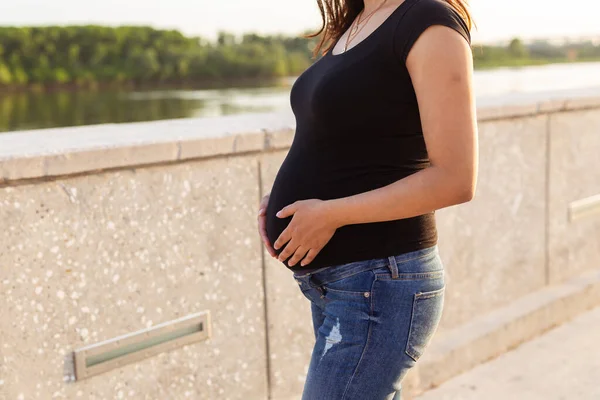 Close-up of pregnant belly outdoors copyspace. Pregnancy and motherhood concept. — Stockfoto