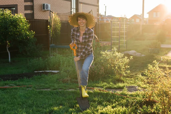 积极的女园丁在阳光灿烂的春日用铲子挖床。新季植物护理及种植概念 — 图库照片