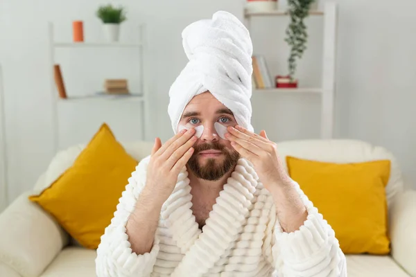 Бородатый мужчина сидит с повязками на лице. Морщины и уход на дому для мужчин. — стоковое фото