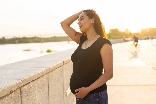 Mulher hispânica grávida no parque, tocando barriga — Fotografia de Stock