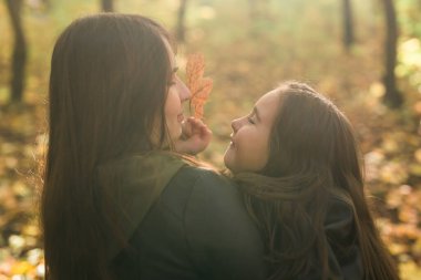 Küçük kız anne sonbahar parkta oynarken