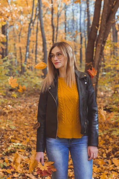 Linda mujer sonriente sosteniendo hojas de otoño en el parque de otoño. Concepto estacional, estilo de vida y ocio. —  Fotos de Stock