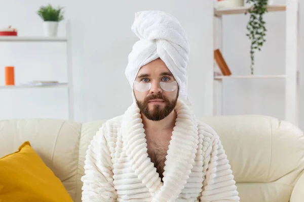 Бородатый мужчина сидит с повязками на лице. Морщины и уход на дому для мужчин. — стоковое фото