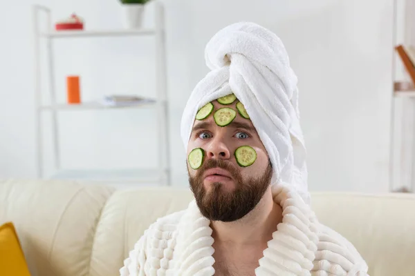 Homem barbudo goza com uma máscara cosmética em seu rosto feita de fatias de pepino. Homens cuidados com a pele e spa em casa conceito — Fotografia de Stock