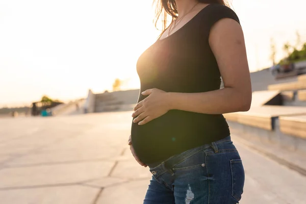 Close-up of pregnant belly outdoors copy space. Pregnancy and motherhood concept. — Stockfoto