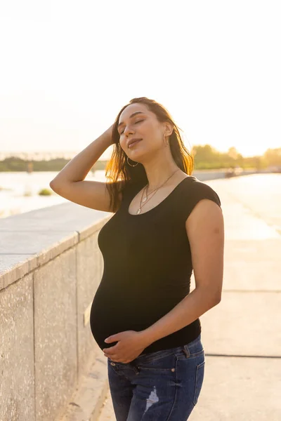 Gravid latinamerikansk kvinna på vall, rörande mage — Stockfoto