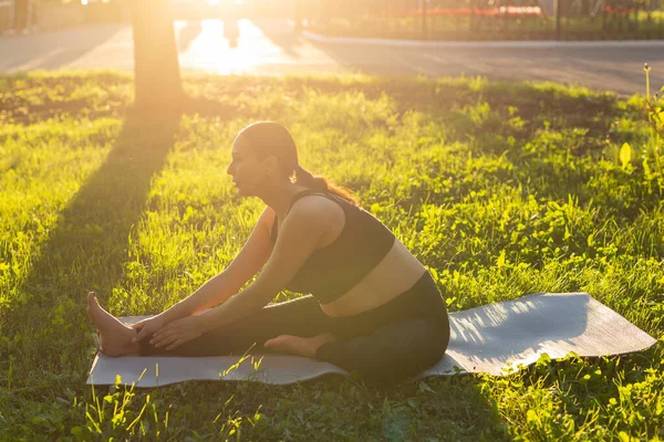 Gravid kvinna som gör yoga i naturen utomhus. Hälsosam livsstil, förväntar baby och fertilitet koncept. — Stockfoto