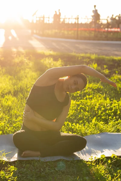 Gravid kvinna som motionerar på gräset på sommardagen. En hälsosam livsstil. — Stockfoto