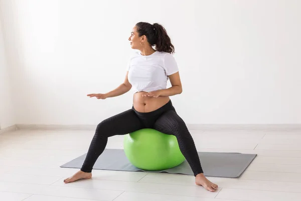 Mujer embarazada alegre baila mientras está sentado en la pelota de fitness. Embarazo de bienestar, estilo de vida saludable y concepto positivo. —  Fotos de Stock